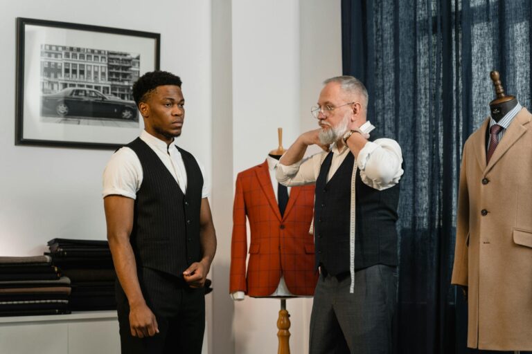 A tailor measures a client in a stylish clothing atelier, showcasing luxury fashion.